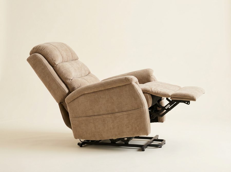 Fauteuil releveur en tissu beige vu de profil, dossier incliné et repose-jambes à l’horizontale, châssis en acier apparent